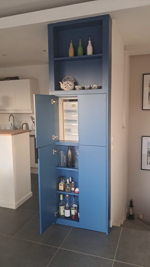 Colonne sur mesure bleue ouverte : cache-tableau électrique et rangement pour bouteilles.