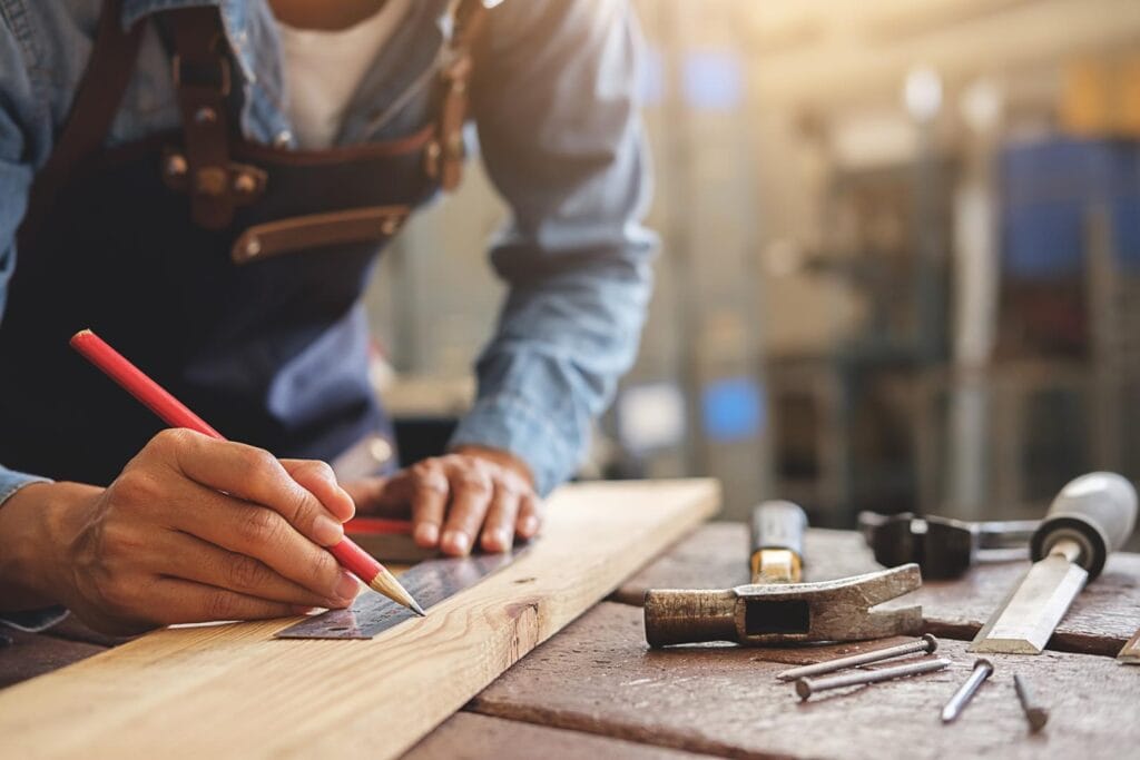 tracé_menuisier Menuisier traçant des repères sur une planche de bois dans son atelier